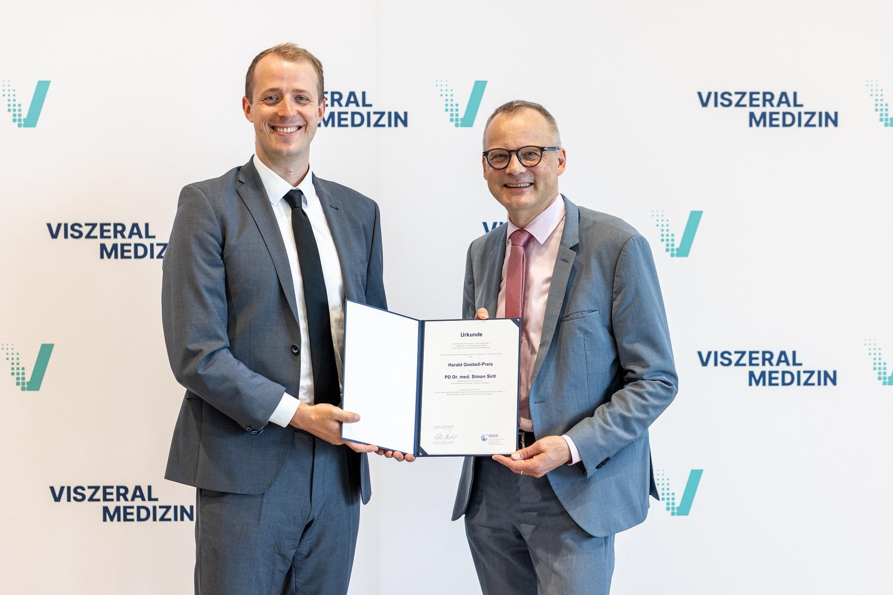 PD Dr. Simon Sirtl (links) erhält die Urkunde zum Harald Goebell-Preis
