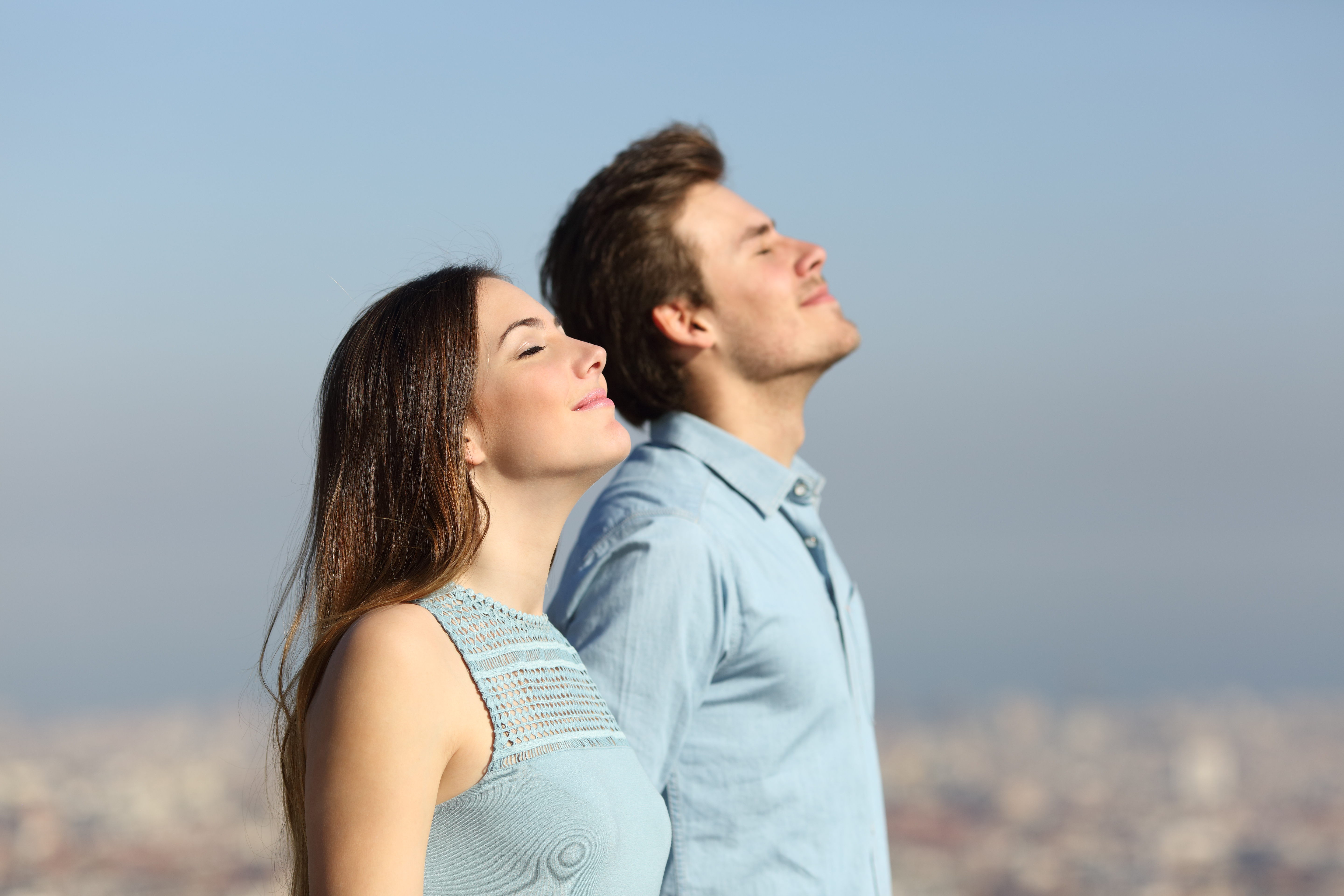 Eine Frau und ein Mann, die ihr Gesicht in die Sonne halten und dabei die Augen geschlossen haben