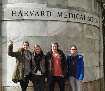 vier Doktoranden vor einer Steinwand auf der "Harvard Medial School" steht