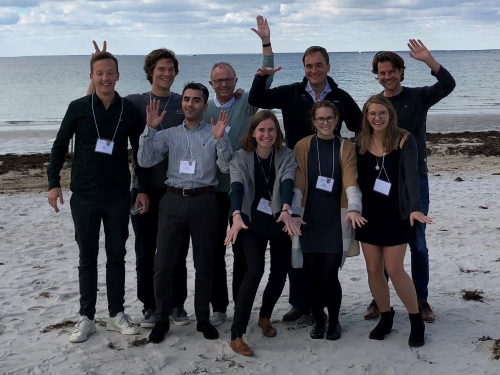 A group of Doctoral students and professors on a beach