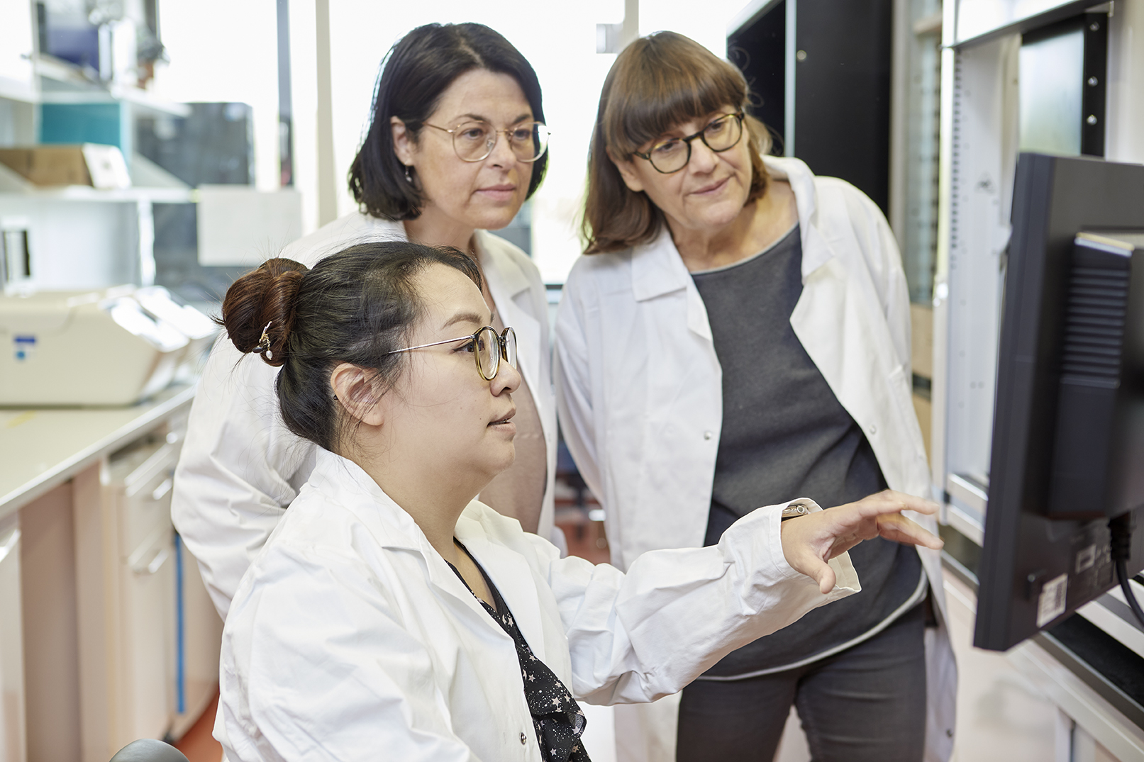  Three researchers in a lab looking at computer screen