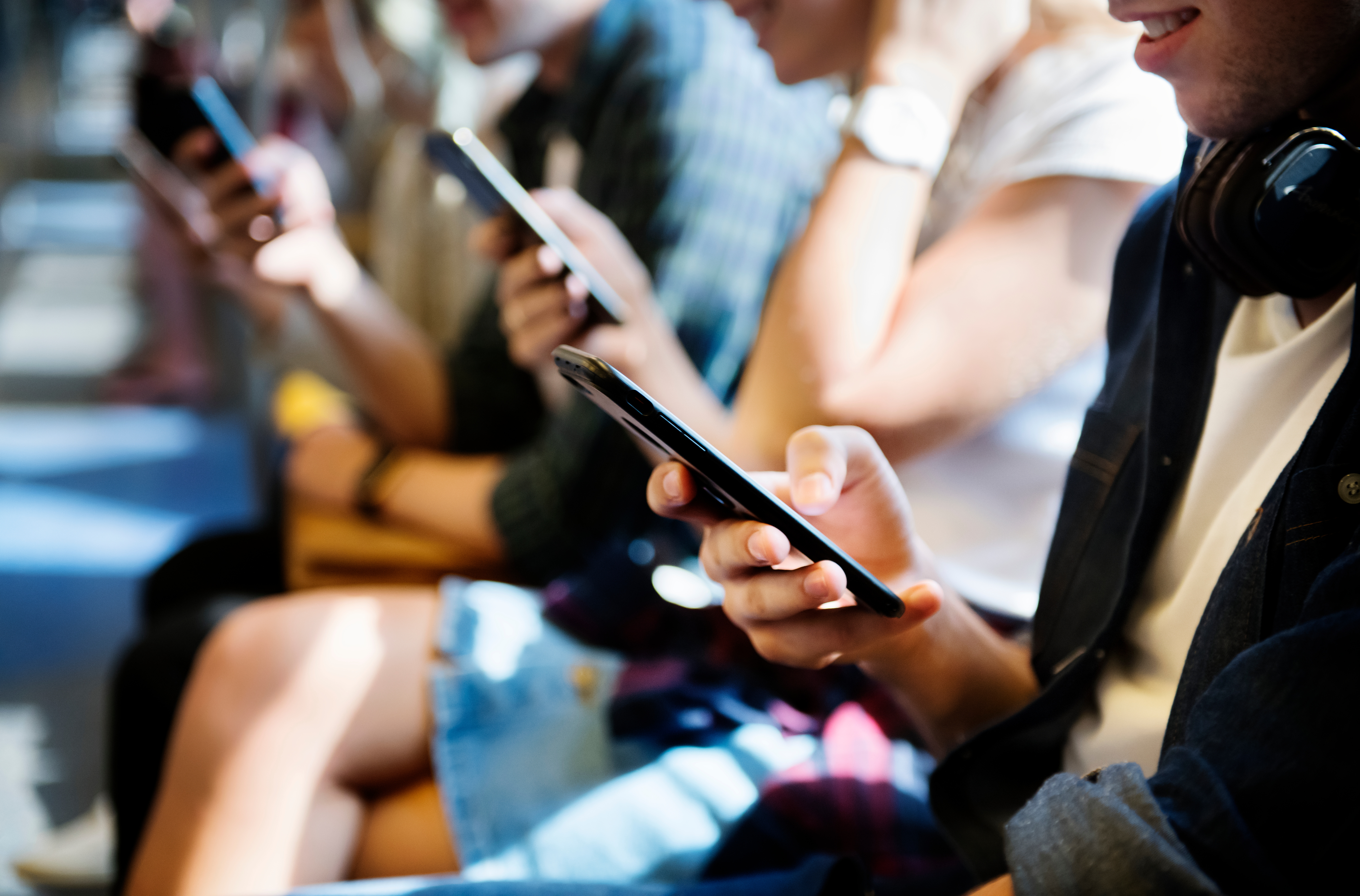 Personen, in einer Reihe, die ihr Smartphone in der Hand halten und darauf blicken