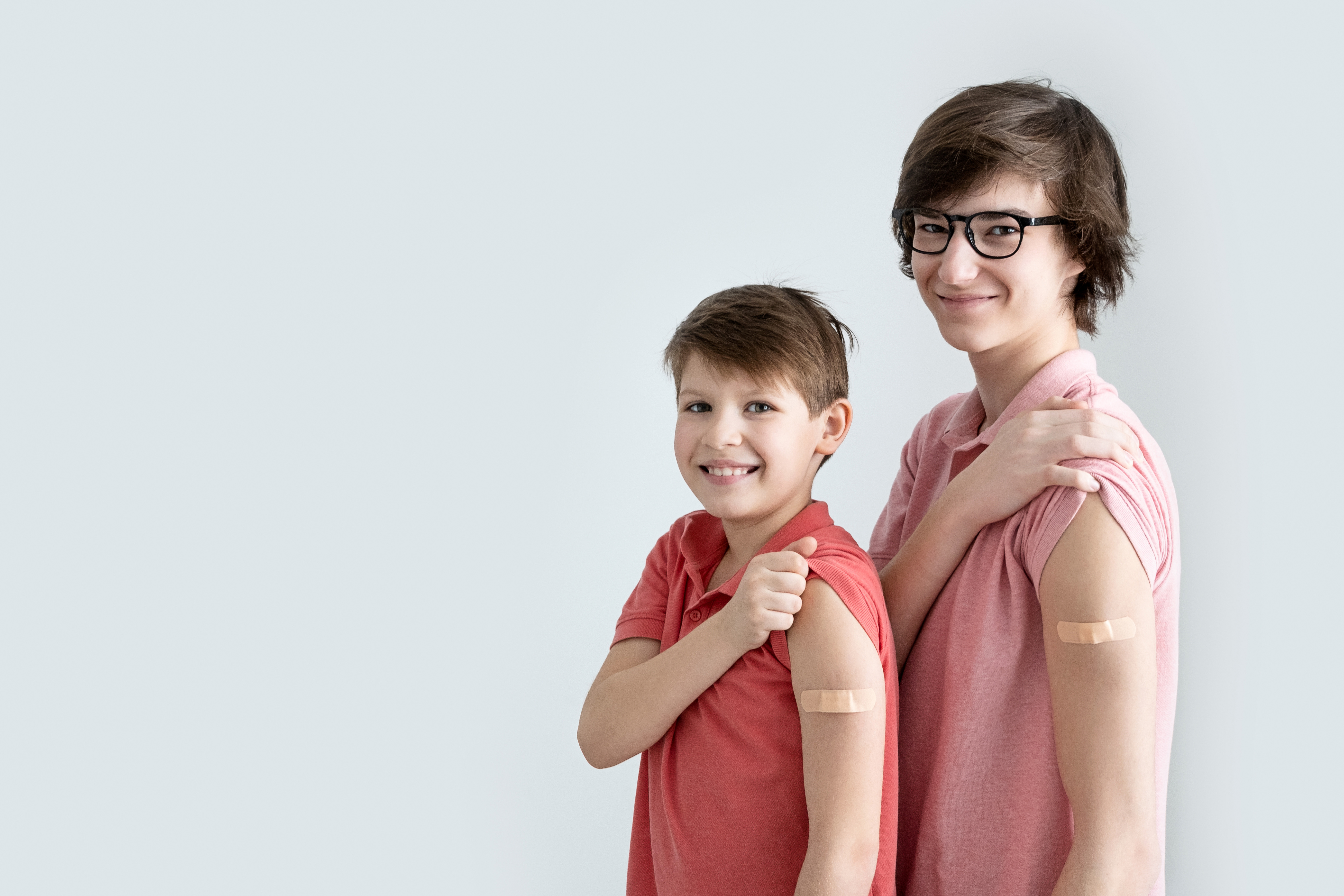 Zwei Jungen, die Pflaster am Oberarm tragen, weil sie gerade geimpft wurden