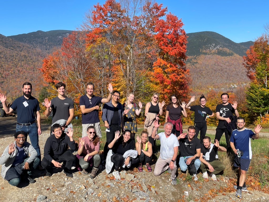 Die Gruppe von Doktoranten die in Amerika sind mit den Professoren auf einem Berg mit bunten Bäumen im Hintergrund