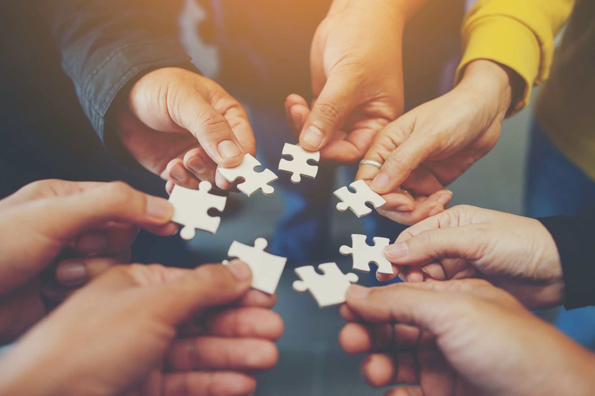 Einzelne Puzzle-Elemente werden von Personen zu einem Kreis gehalten
